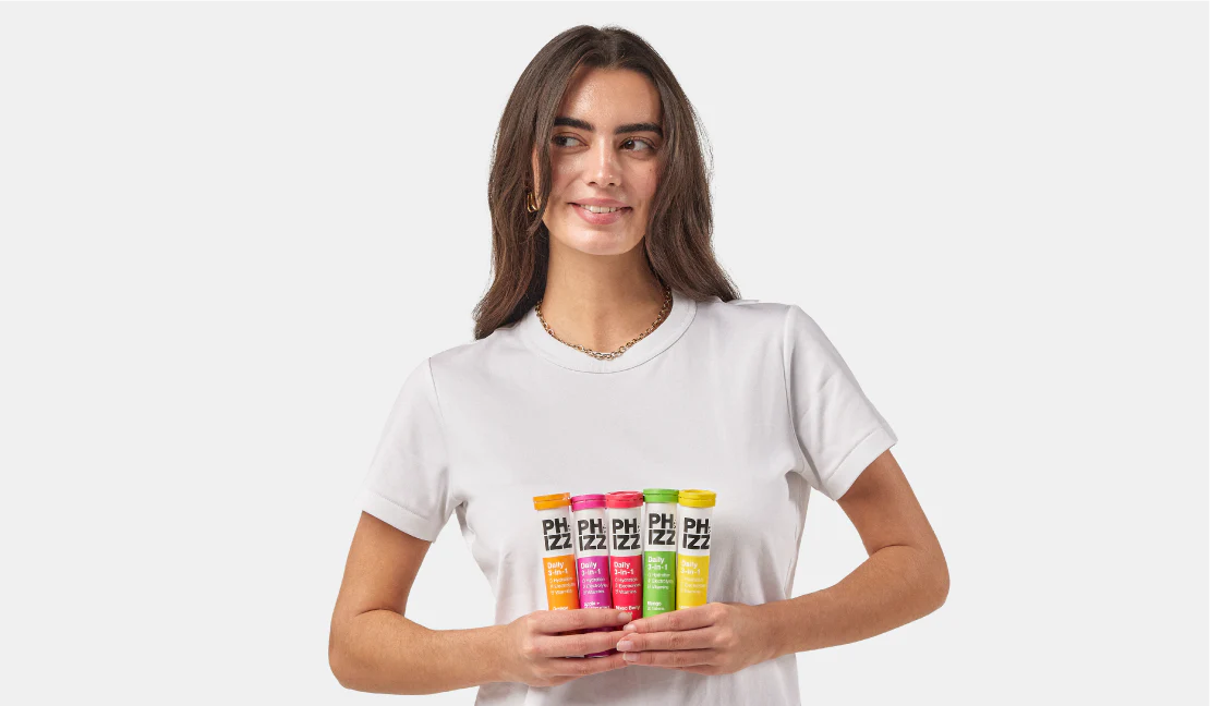 Person in a white t-shirt holding four tubes of Phizz hydration tablets