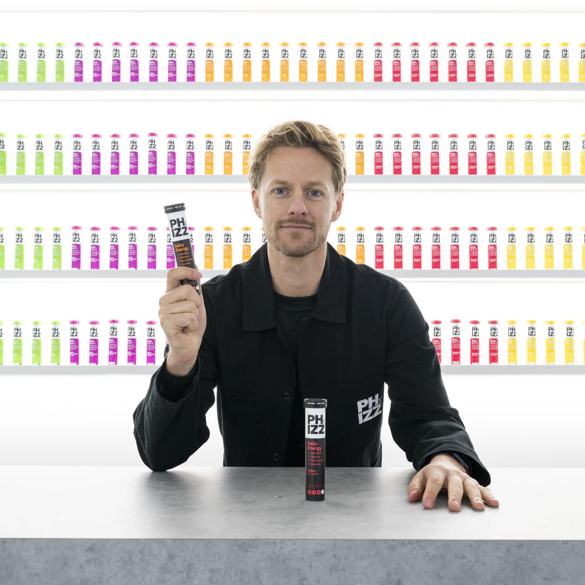 Person holding a Phizz tube in front of a wall of Phizz products